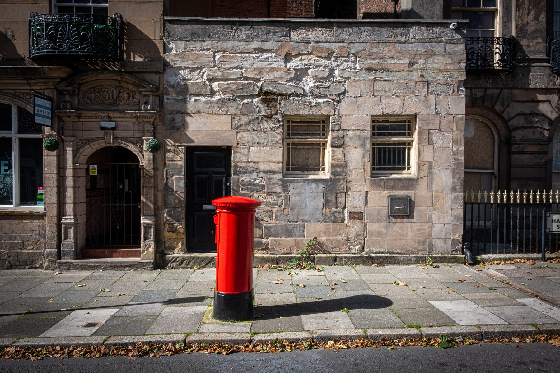 Red pillar box against a stone facade