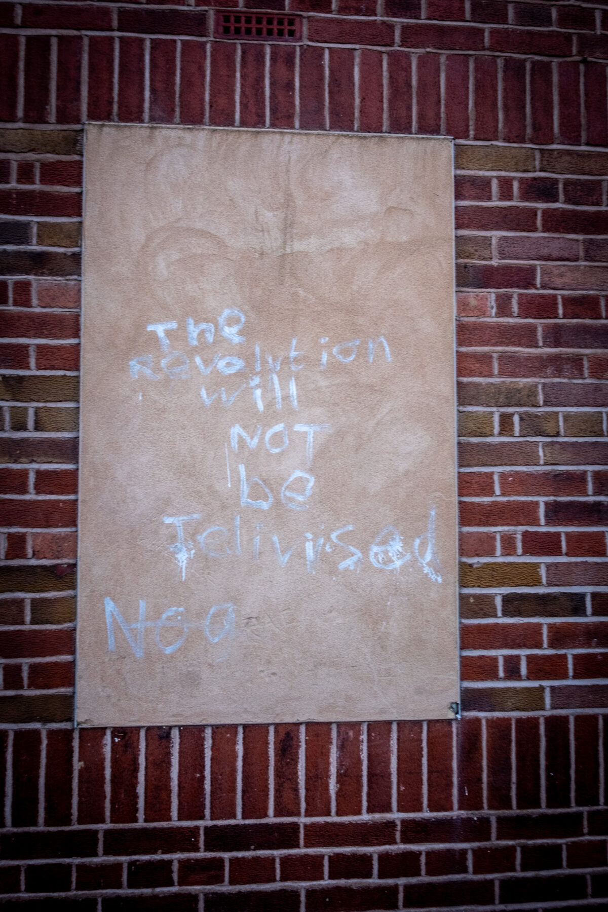 Boarded window with 'the revolution will not be televised' written on it