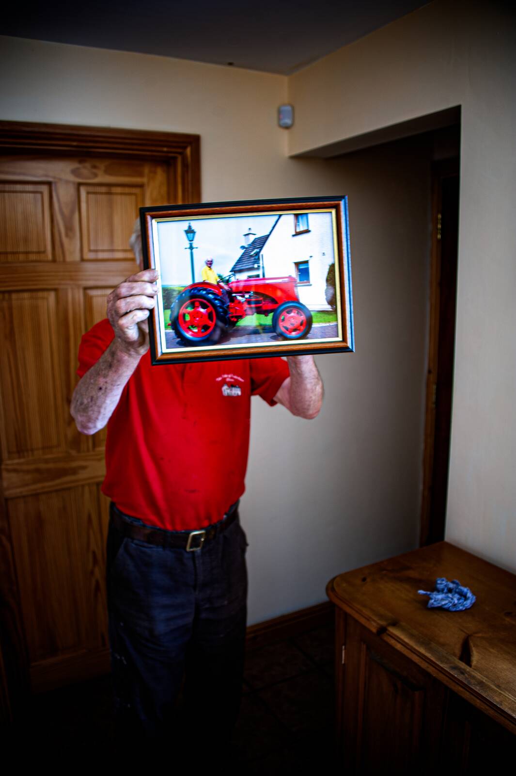 Bill Moffat holding a framed tractor photograph in front of his face