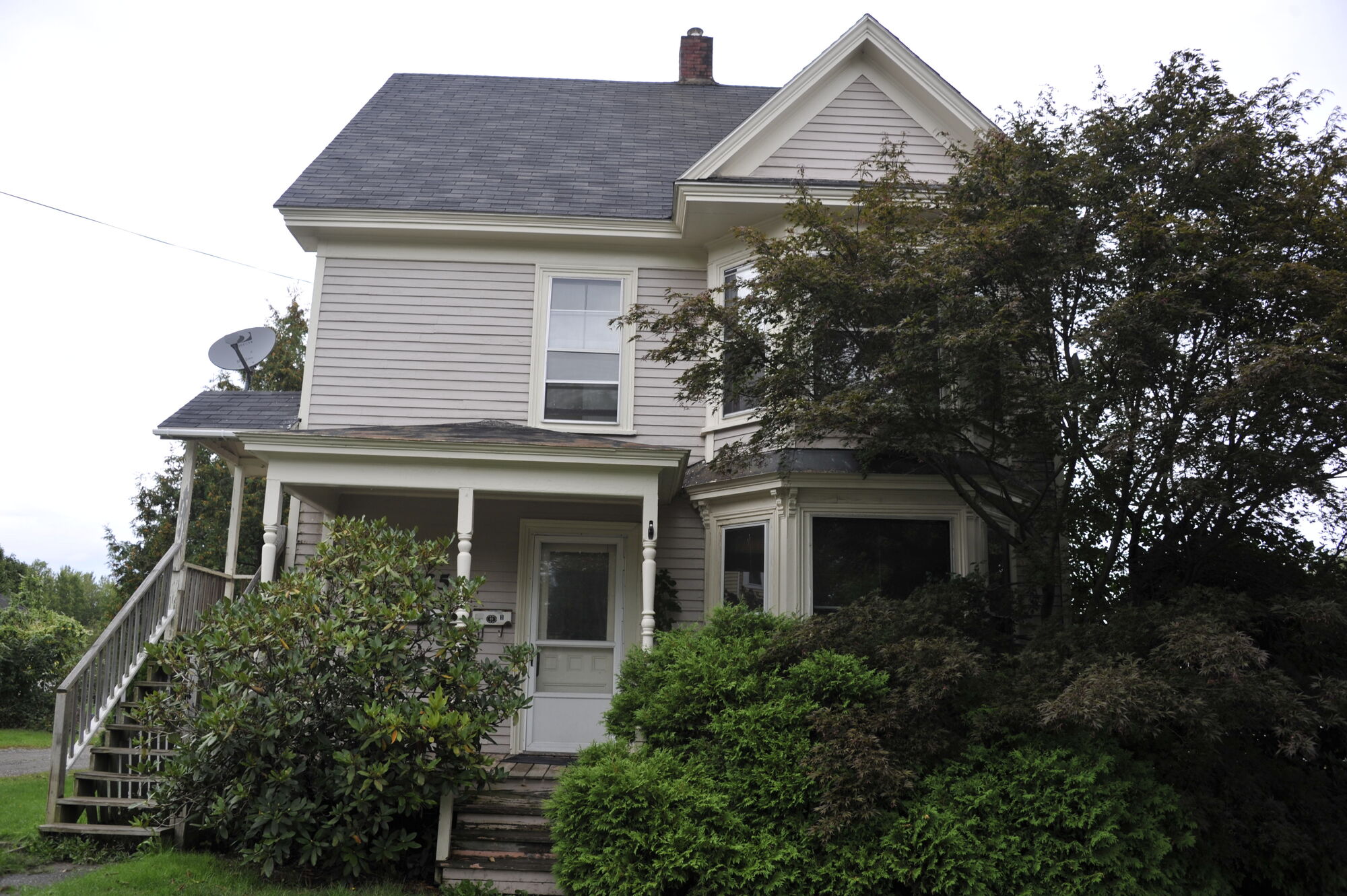 Front elevation of 725 — a two-storey clapboard house behind trees